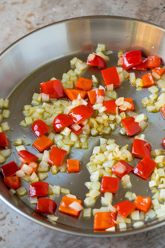 Red bell peppers and onions cooked in a pan.